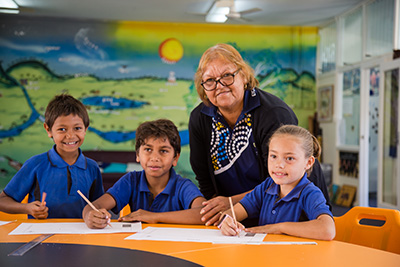 A teacher posing with three students in the classroom